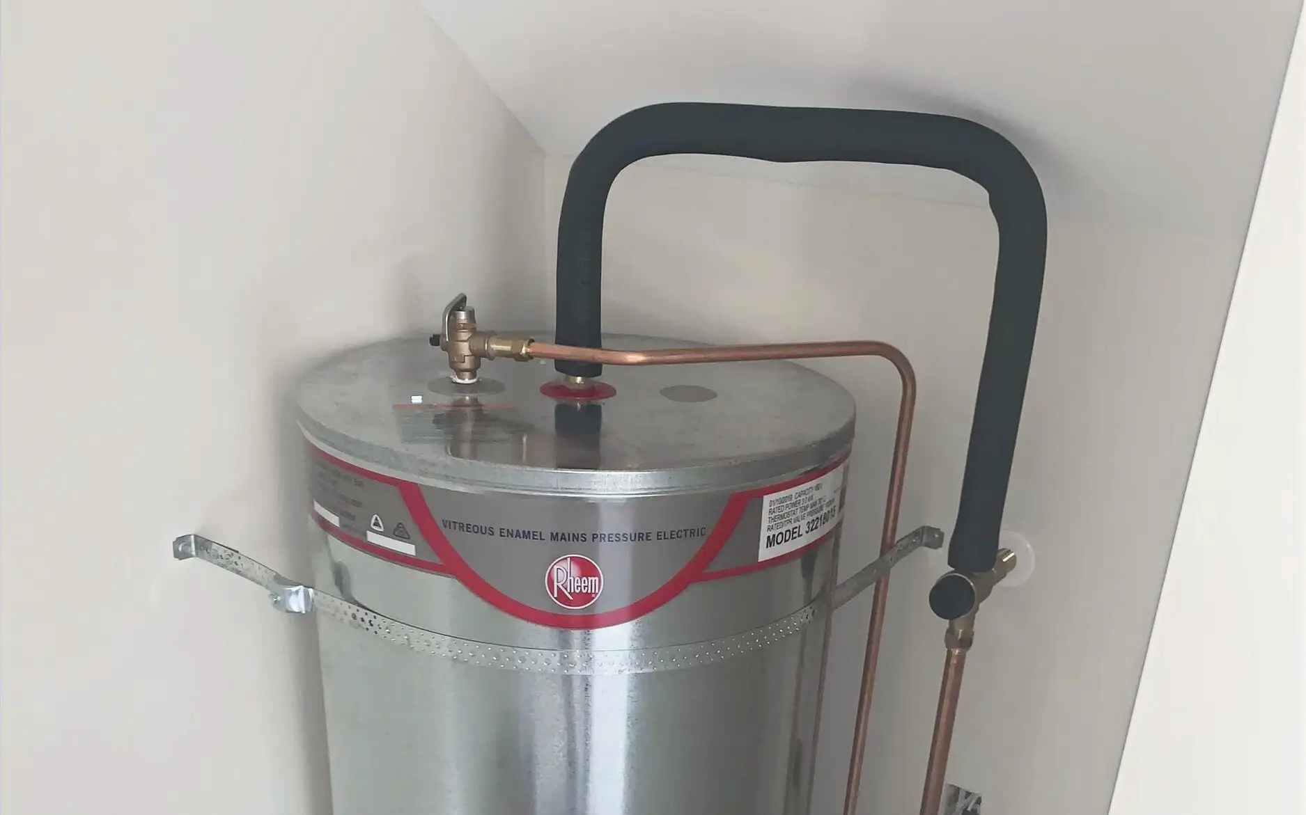 Top of a mains pressure hot water cylinder, showing the relief valve and its copper drain line