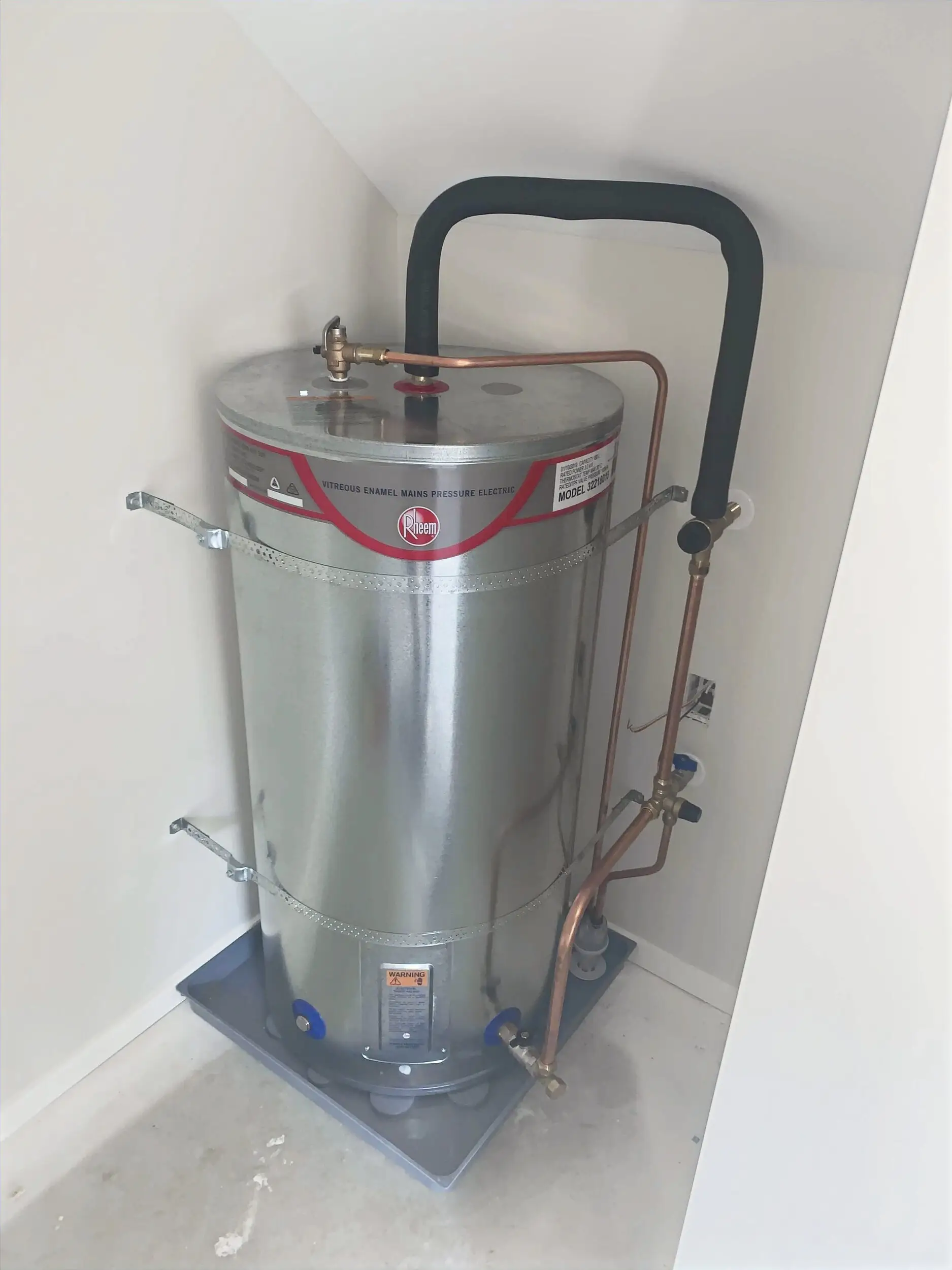 New electric hot water cylinder installed in a laundry cupboard with copper pipework