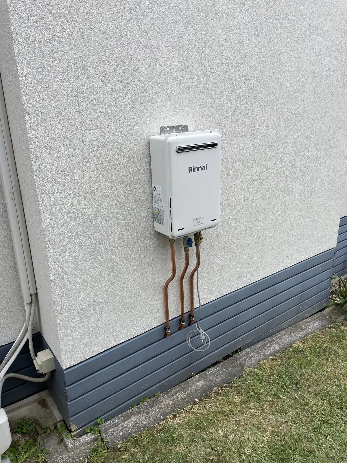 Gas califont, a continuous flow gas hot water unit, on a white exterior wall