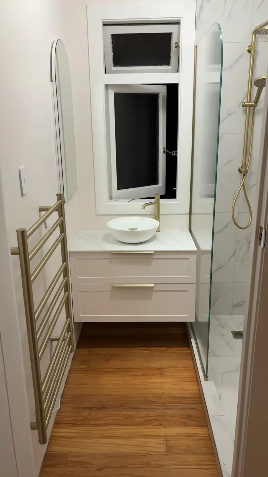 After: finished white bathroom with brass tapware and heated towel rail