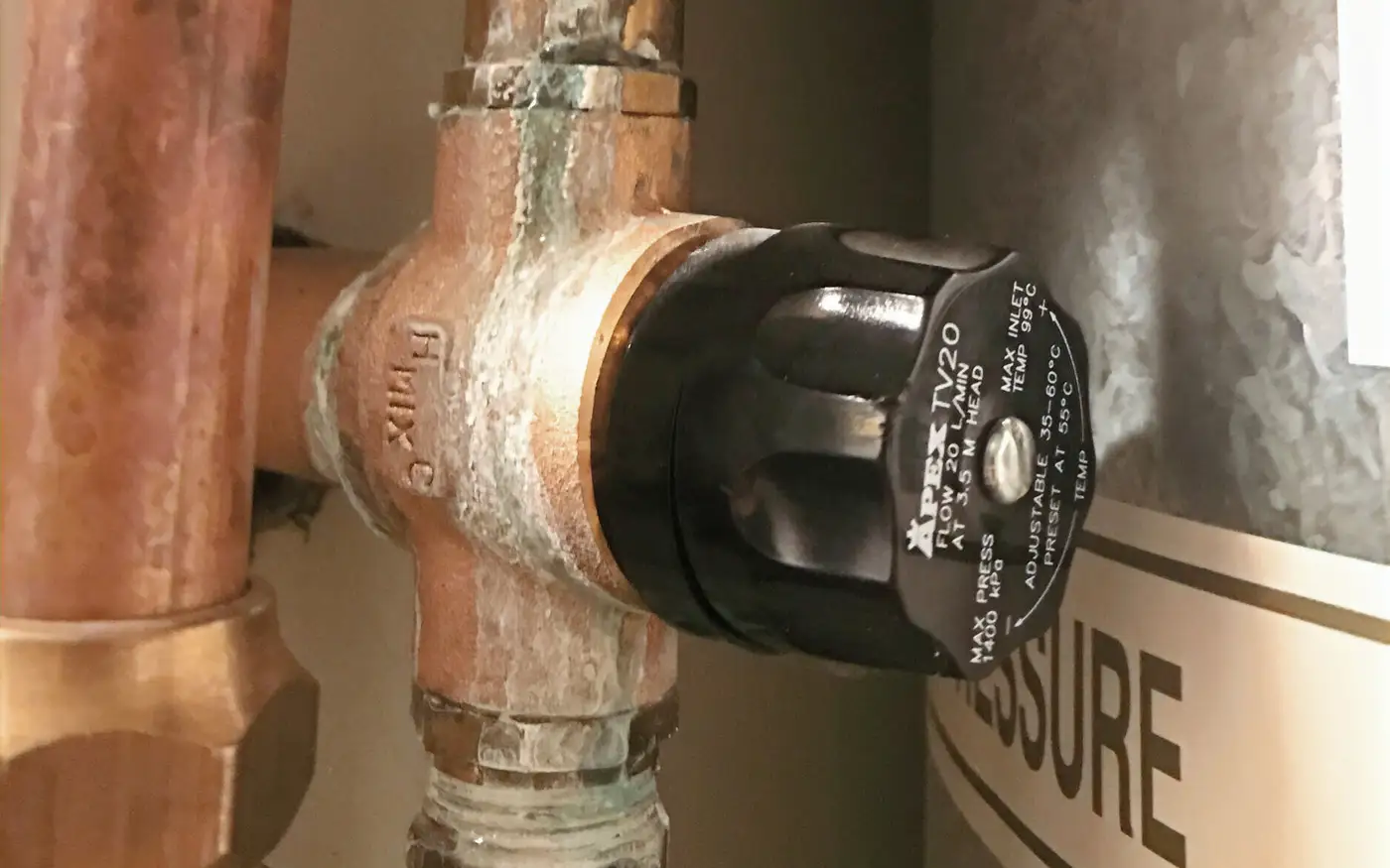An Apex tempering valve on the copper pipework beside a mains pressure hot water cylinder